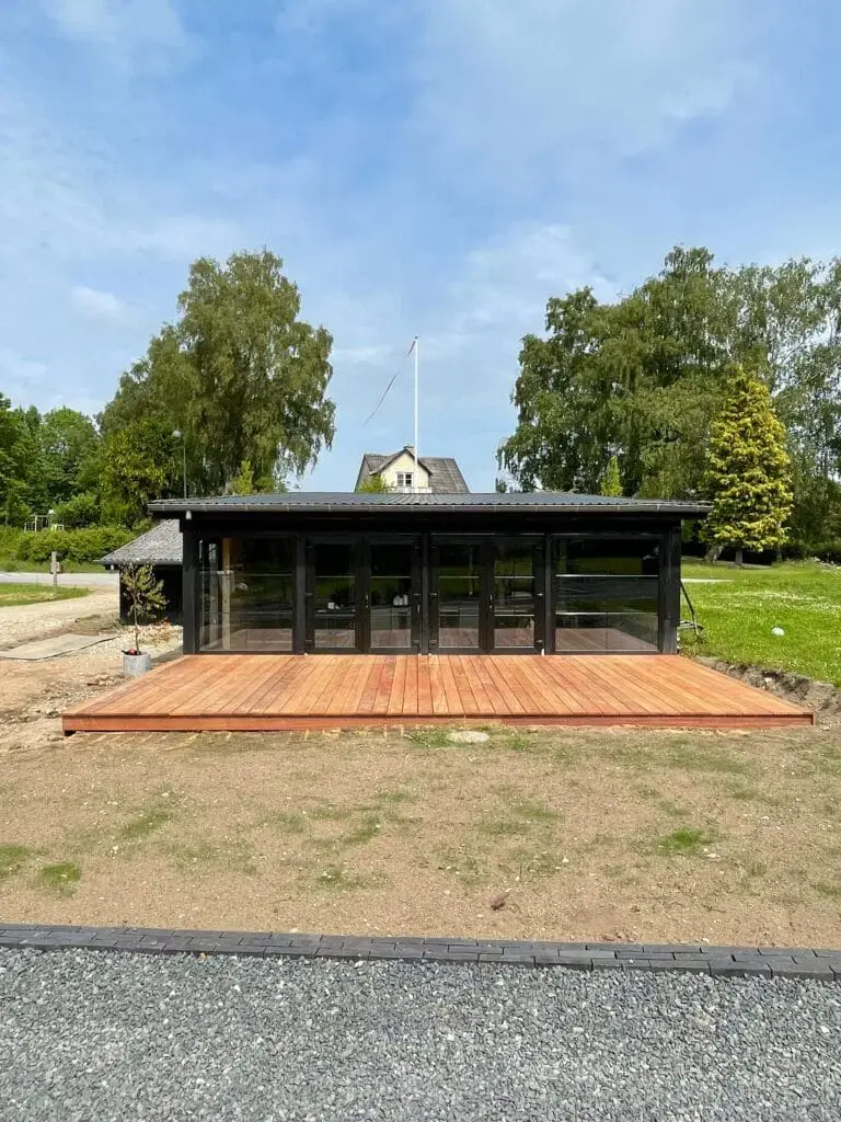 Ny træterrasse foran et sort sommerhus